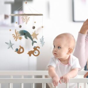ocean whale crib mobile hanging above baby crib, gender neutral nursery decor coastal theme mobile with soft whale shapes for baby room