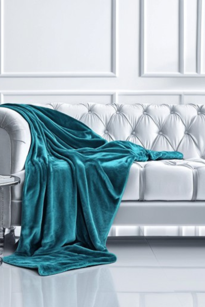 White tufted sofa with teal throw blanket in a mid-century modern living room