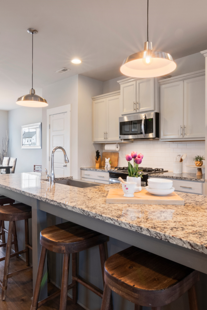 Bright kitchen with white cabinets, granite countertops, bar stools, and simple countertop decor